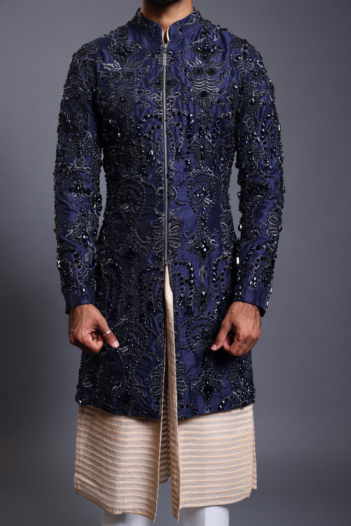 Sophisticated navy silk sherwani with shimmering crystal, bead, and zircon embellishments, paired with a sleek stripwork kurta