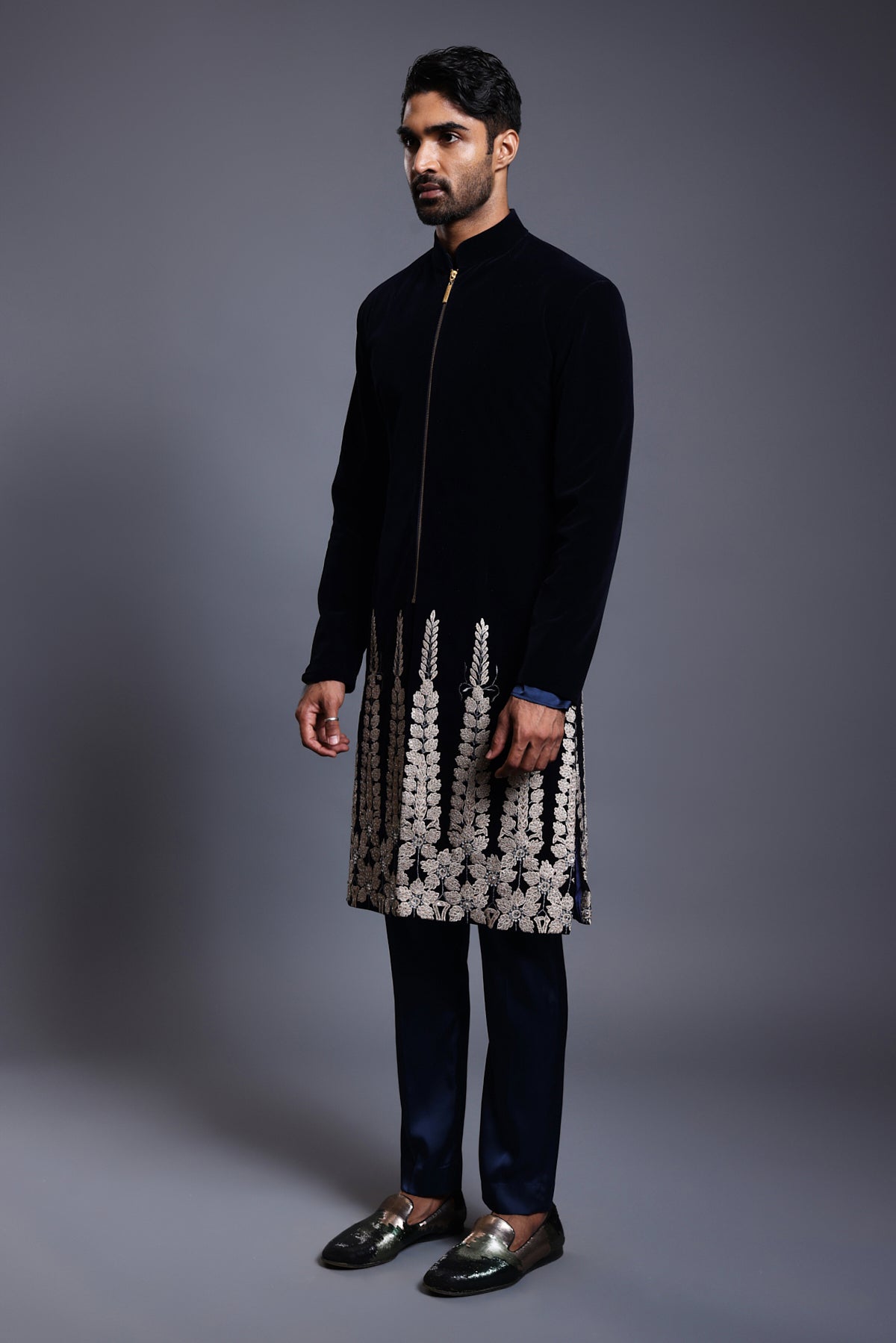 Luxurious navy sherwani in soft velvet, adorned with intricate floral applique detailing and sparkling crystals along the hem, ideal for a regal wedding look