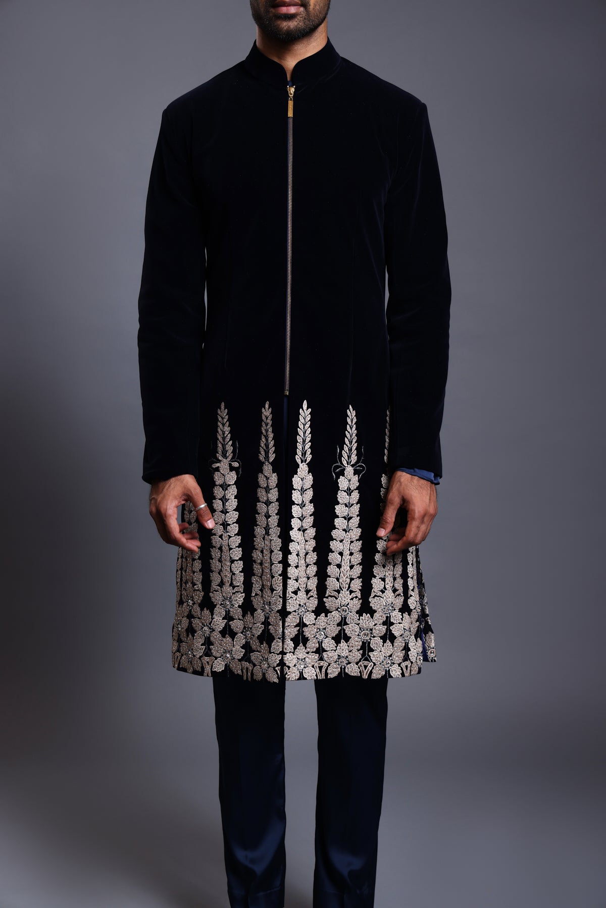 Elegant navy velvet sherwani featuring delicate floral applique and shimmering crystals on the hem, combining traditional craftsmanship with modern luxury.