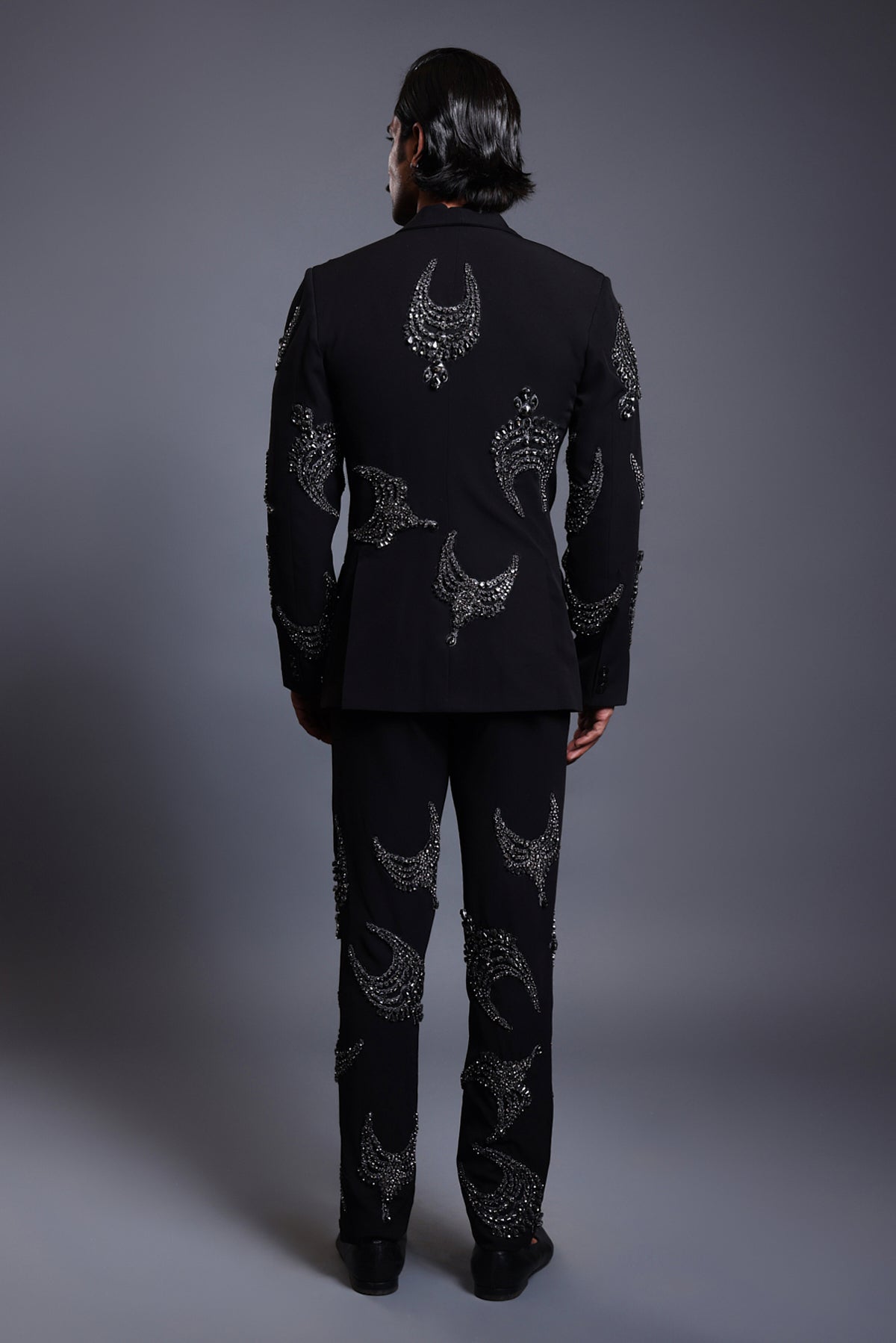 Stylish black suit with crystal necklace crests, blending contemporary design with timeless luxury.