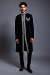 Black velvet sherwani with a crystal border, adorned with a necklace crest.