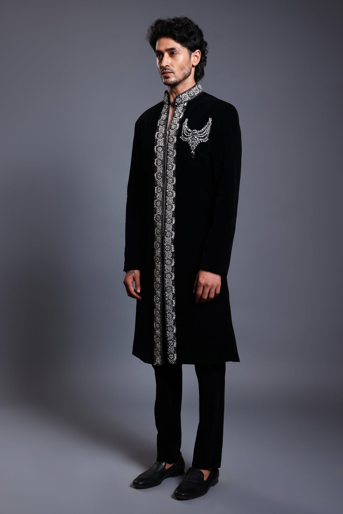 Elegant black velvet sherwani featuring a crystal-bordered design and a necklace crest