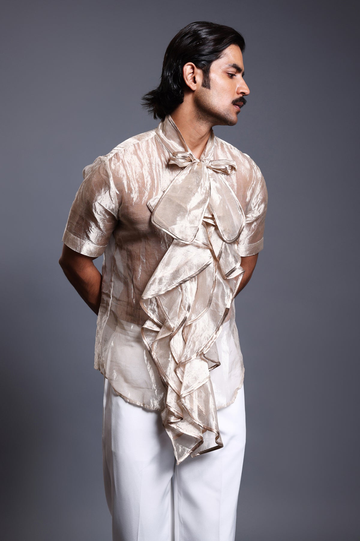 Close-up of gold tissue shirt featuring a cascading design and an elegant bow detail.