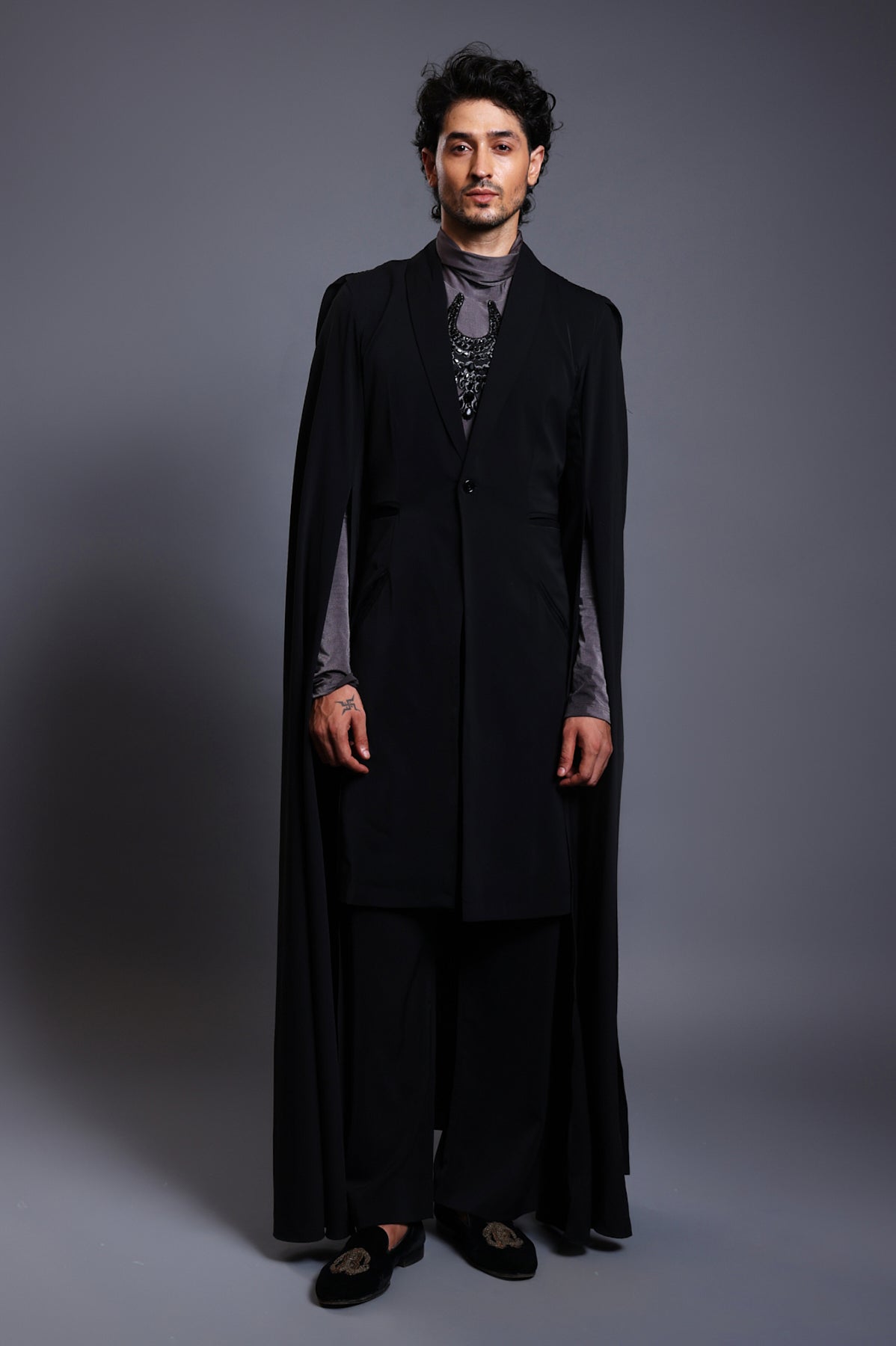 Close-up of black overcoat with fluid draped sleeves and an elegant cape