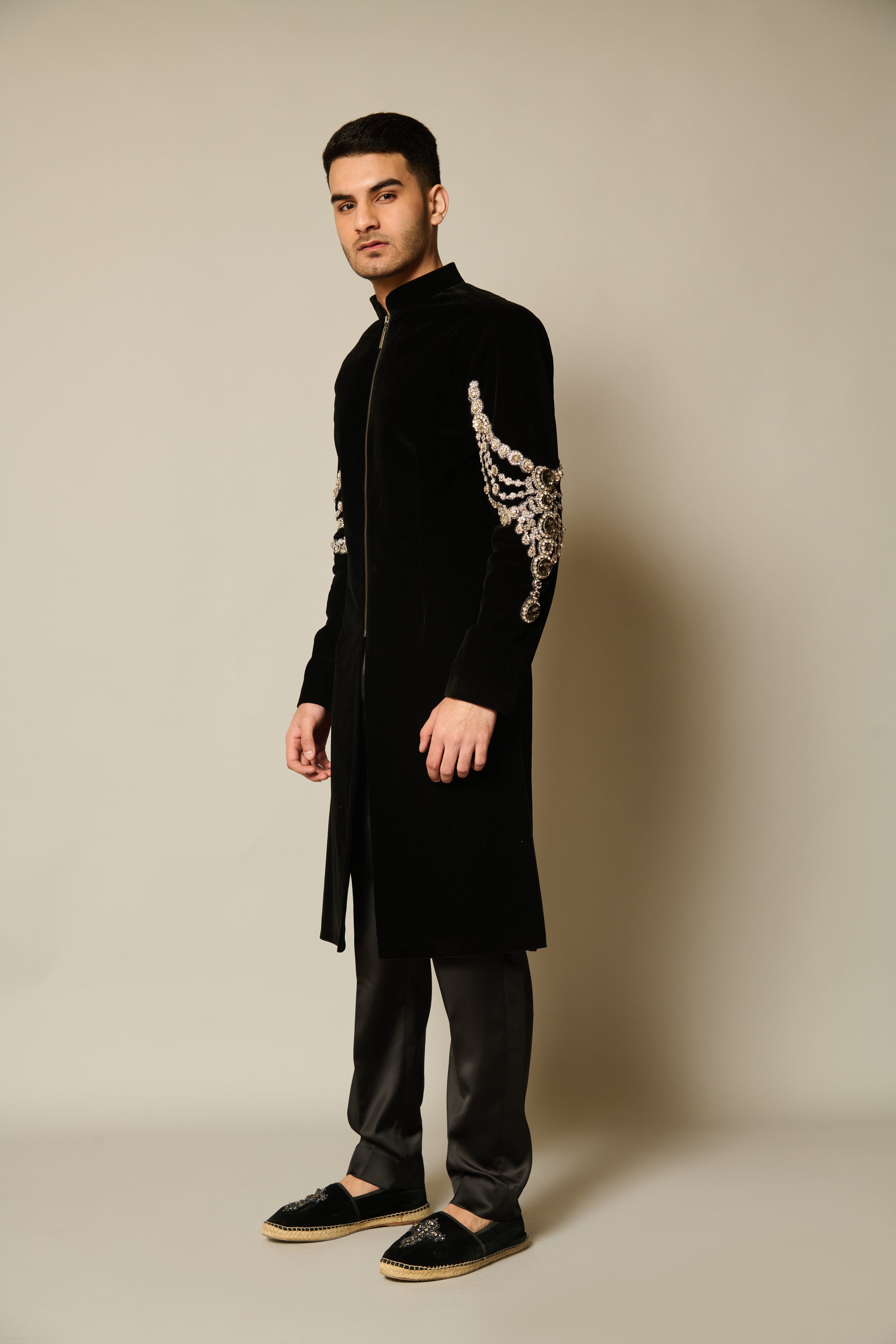 Close-up of black velvet sherwani featuring intricate crystal embroidery on the sleeves, creating a shimmering effect.