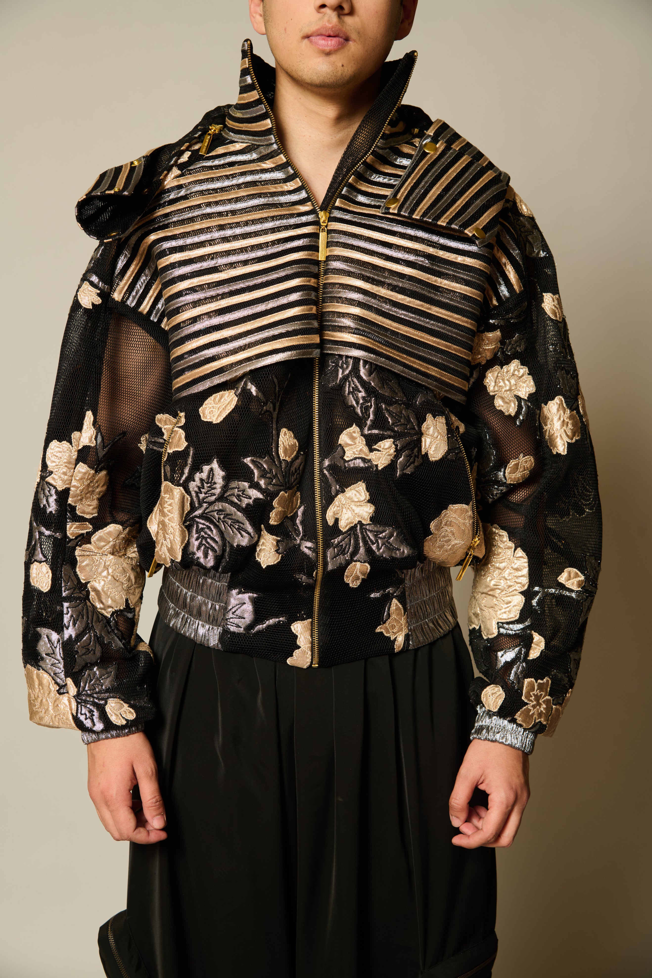 Chic black neoprene mesh jacket with a marshmallow-like texture, embellished with metallic strips and floral applique.