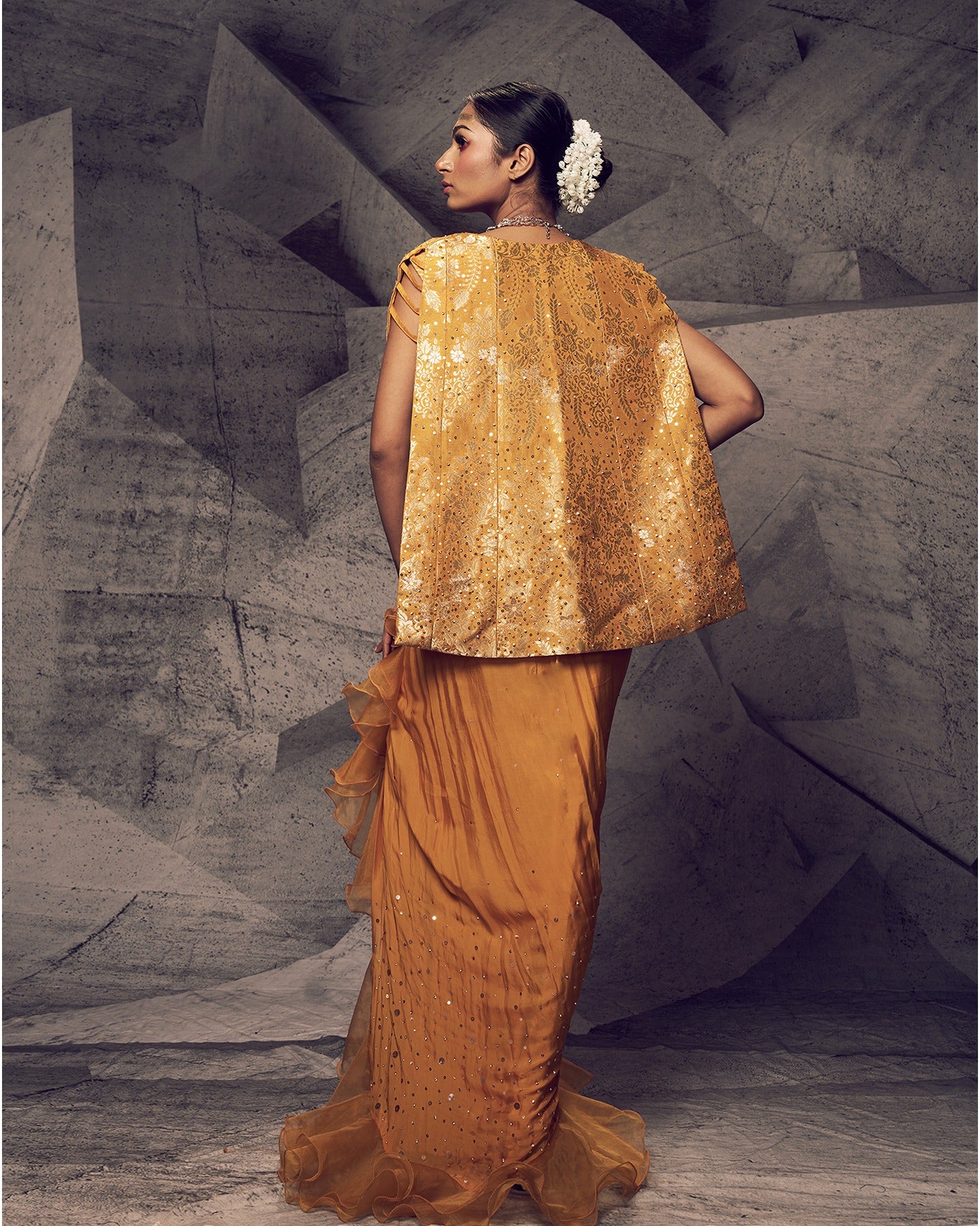 Bathed in the radiant hues of marigold, this embellished dhoti ensemble is a celebration of festive elegance. 