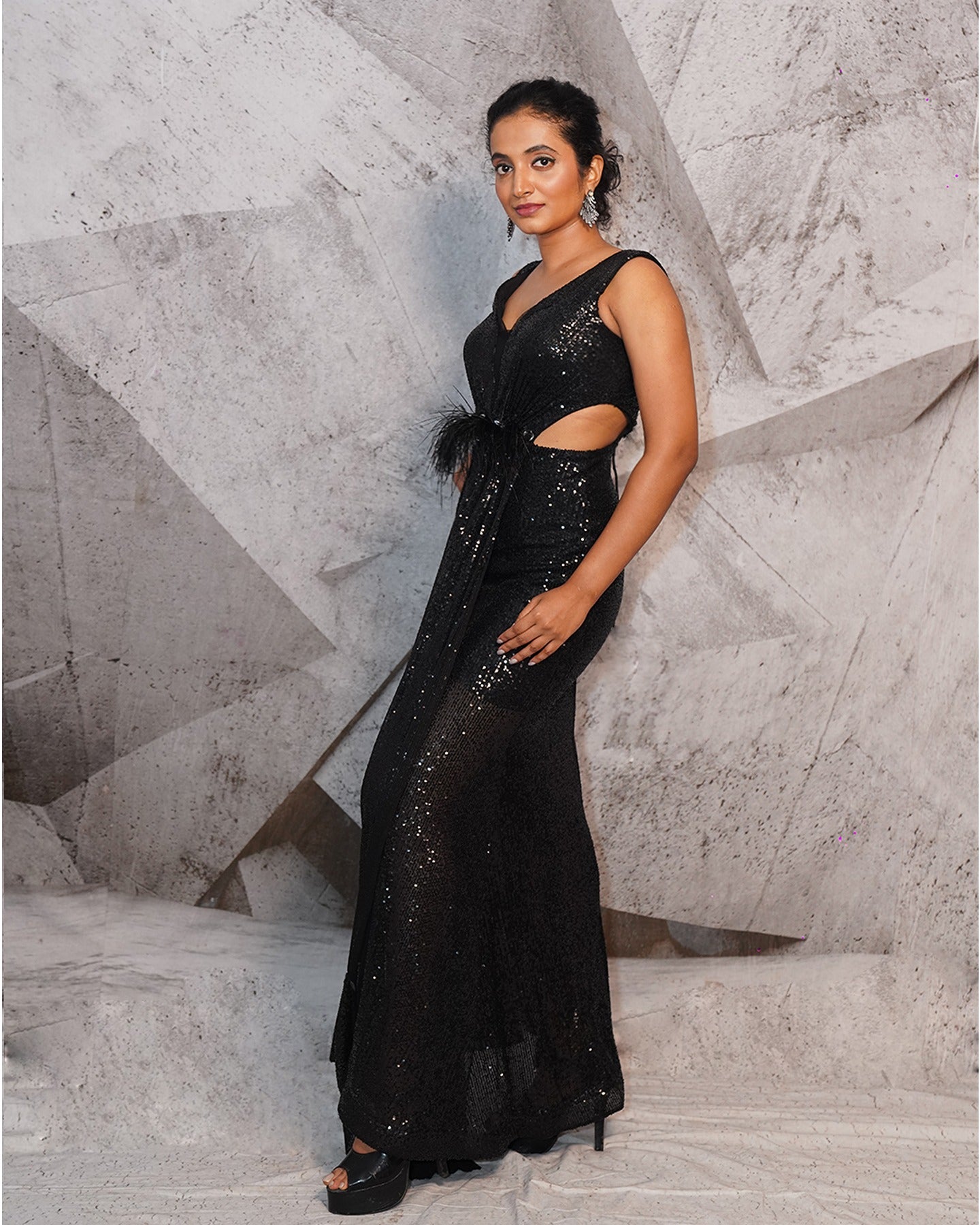 Draped in the midnight elegance of black, this gown speaks volumes with its glittering sequins and a touch of 3D feathers.